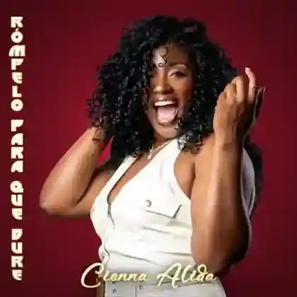 Cienna Alida laughing in a white outfit against a red backdrop