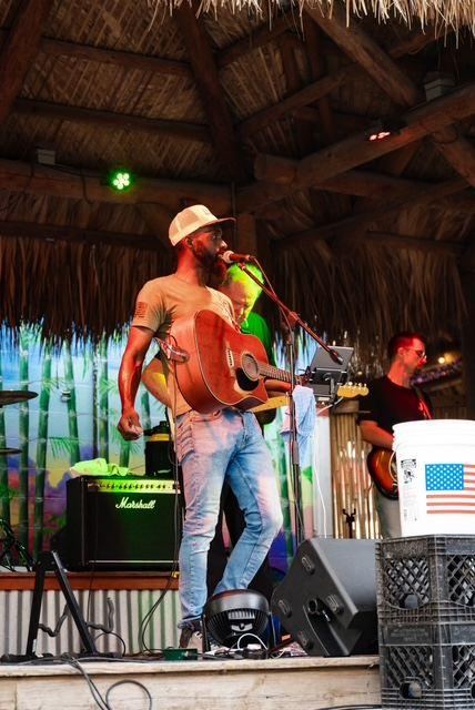 Jesse Daniels performing with acoustic guitar and band on an outdoor stage