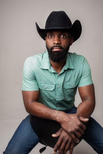Jesse Daniels in a black cowboy hat and green shirt, studio portrait
