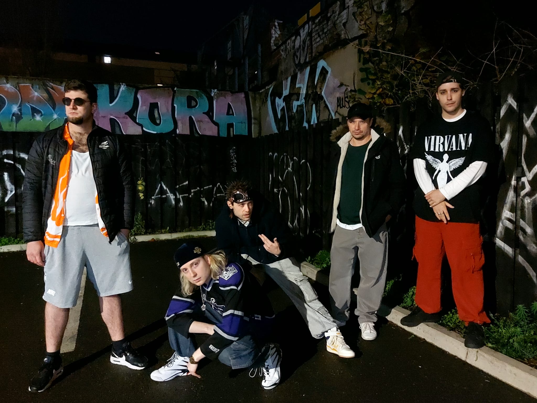 Velour Fog full band on a night street in front of graffiti